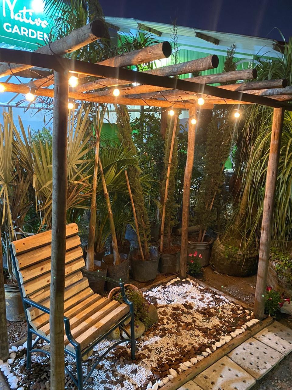 Pergolado de madeira do Sítio Nativo Garden, com banco e luzinhas