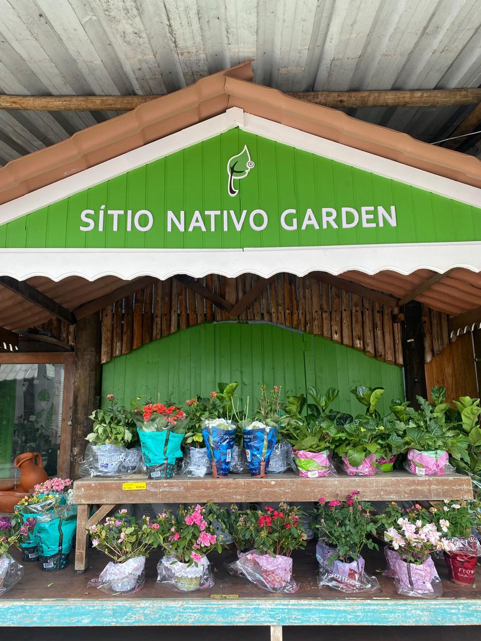Entrada do Sítio Nativo Garden, com o balcão de plantas floridas embaixo da placa